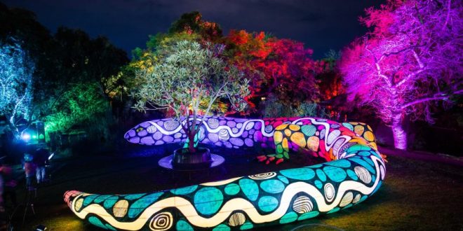 A photo of a colourful statue of a giant snake, lit up by multi-coloured lights.