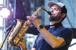 A man wearing a cap playing saxophone on stage.