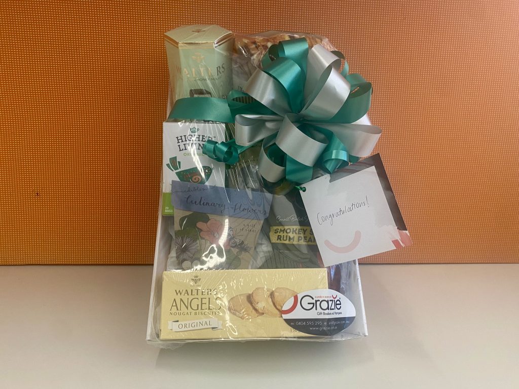 Gift basket wrapped in plastic with a green and silver bow and card reading Congratulations!